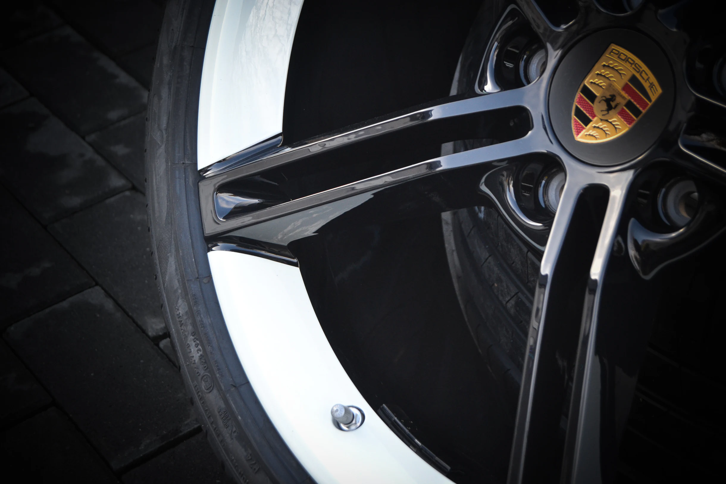 Detail der schwarzen Speichen und des weißen Felgenbetts einer Porsche-Felge bei AT Plus.