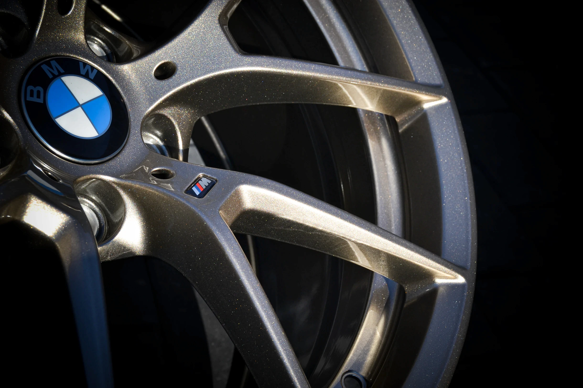 Nahaufnahme der Nabenpartie, verzweigten Speichen und M-Plakette einer BMW-Felge bei AT Plus.